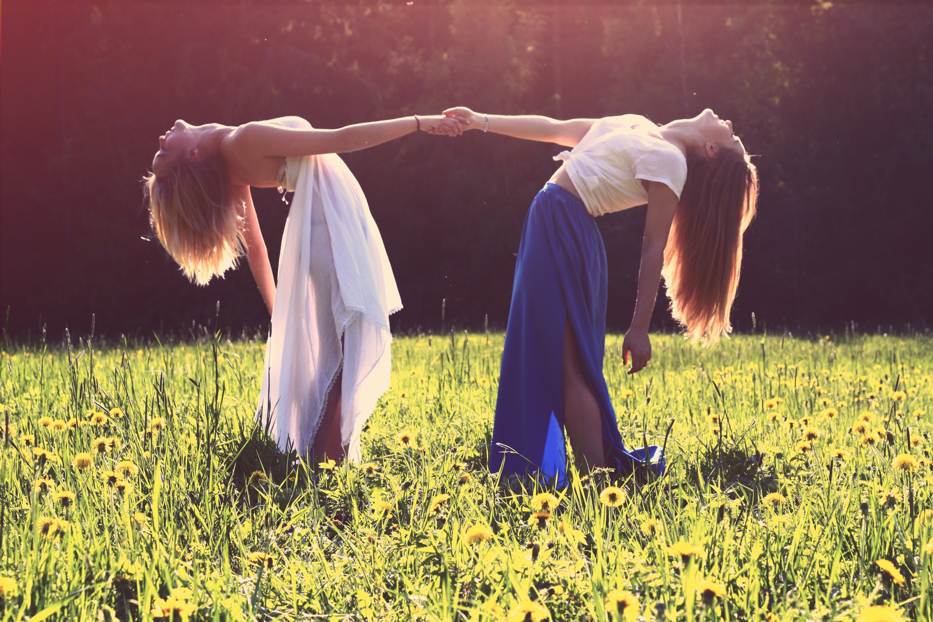 two women bending while holding hands